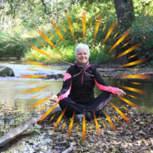 Coach en hypnose, Simone Grunfelder, assise en méditation près d'une rivière avec un halo de lumière symbolisant la libération des émotions bloquées et le bien être intérieur